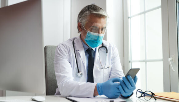 Aktualizacja drEryk eGabinet 3.15 - lekarz siedzący w gabinecie, przeglądający wiadomości na smartfonie